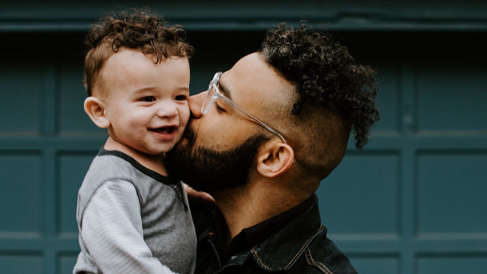 father kissing child and smiling